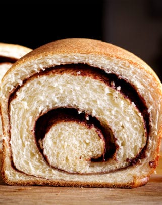 A loaf of homemade cinnamon bread, cut in half so you can see the cinnamon swirl inside.