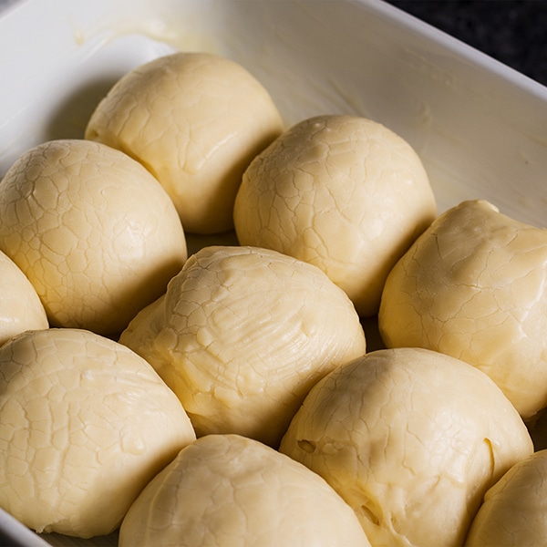 A pan of dinner rolls, fully risen, and ready to bake.