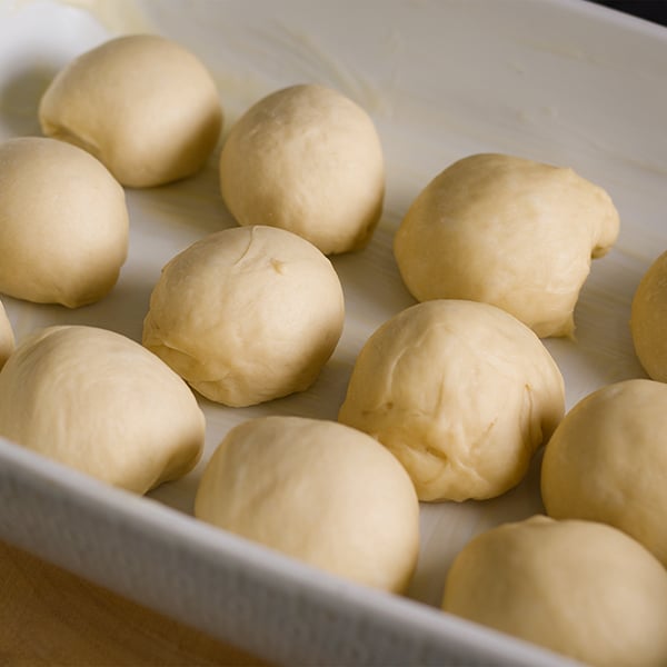 A pan of dinner rolls that have just been shaped and need to rise before baking.