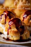 A plate of homemade profiteroles filled with vanilla ice cream and drizzled with sweet wine dessert sauce.