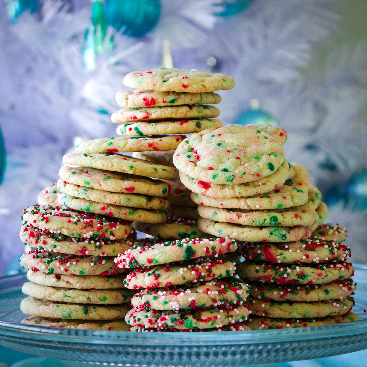 Stacks of Christmas funfetti cookies towering high on a glass platter.