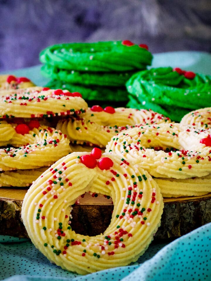A wood platter piled high with Spritz wreath Christmas cookies.