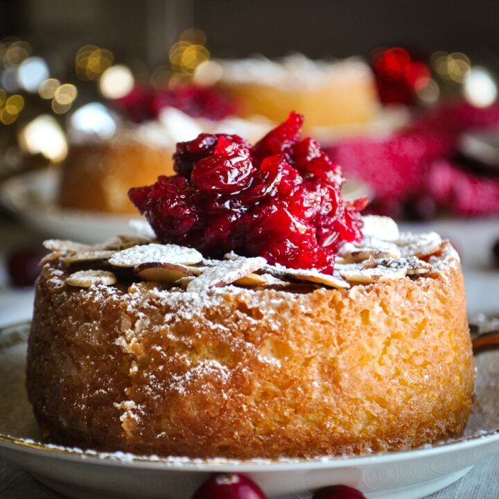 An almond cake topped with cranberry sauce on a plate ready to eat.