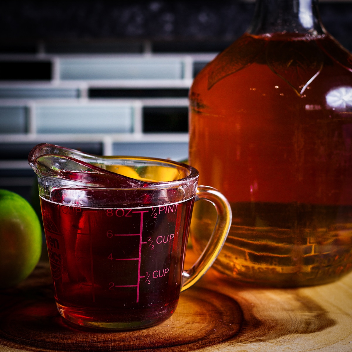 A glass measuring cup filled with apple cider that's been reduced into a thick syrup.