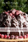 A Gingerbread Cake covered in sugared cranberries and lemon glaze on a wood serving platter, ready to serve.