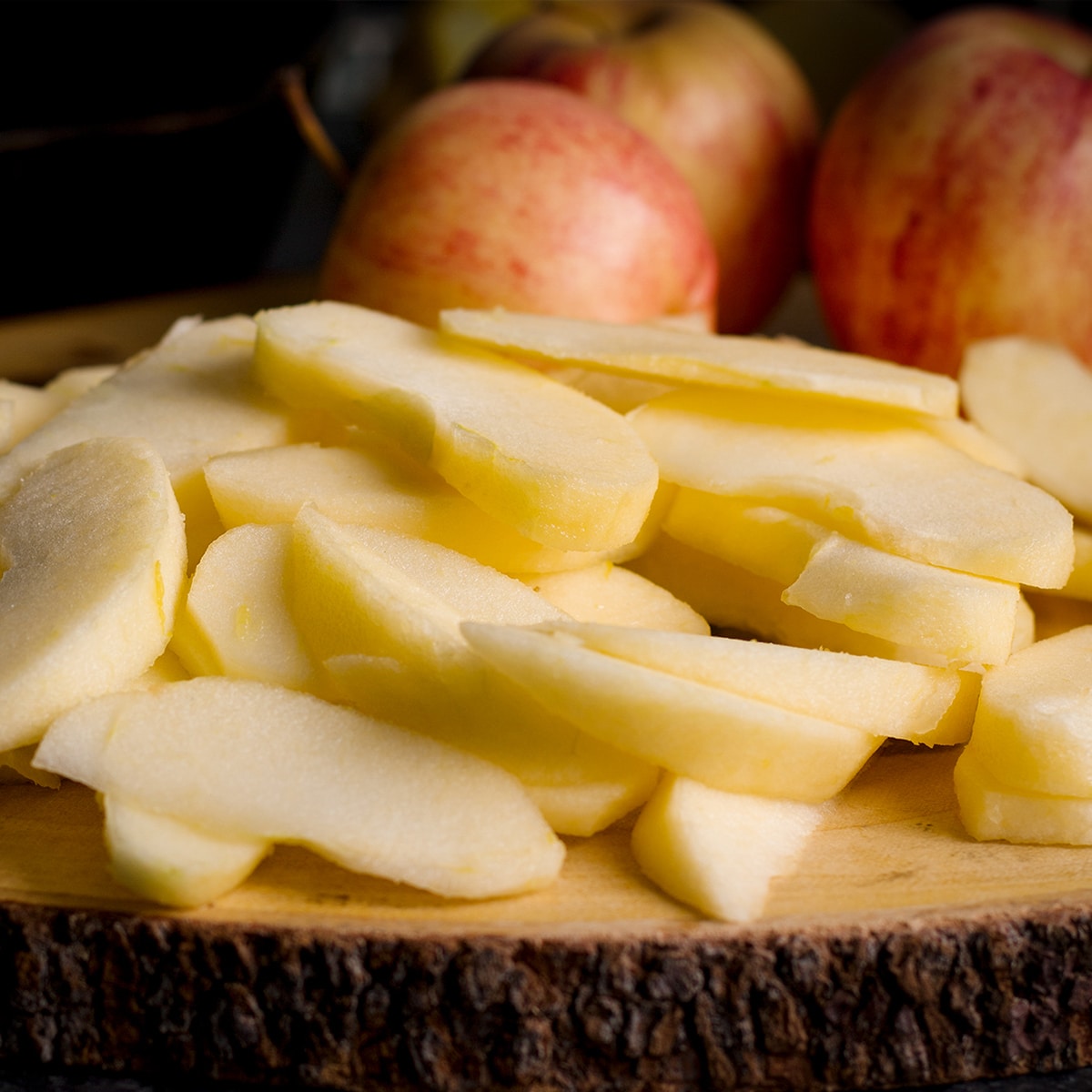 A pile of sliced apples on a wood cutting board.