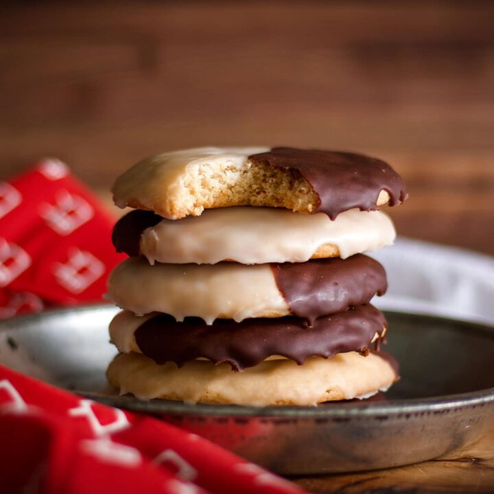 A stack of homemade New York black and white cookies on a tin plate.