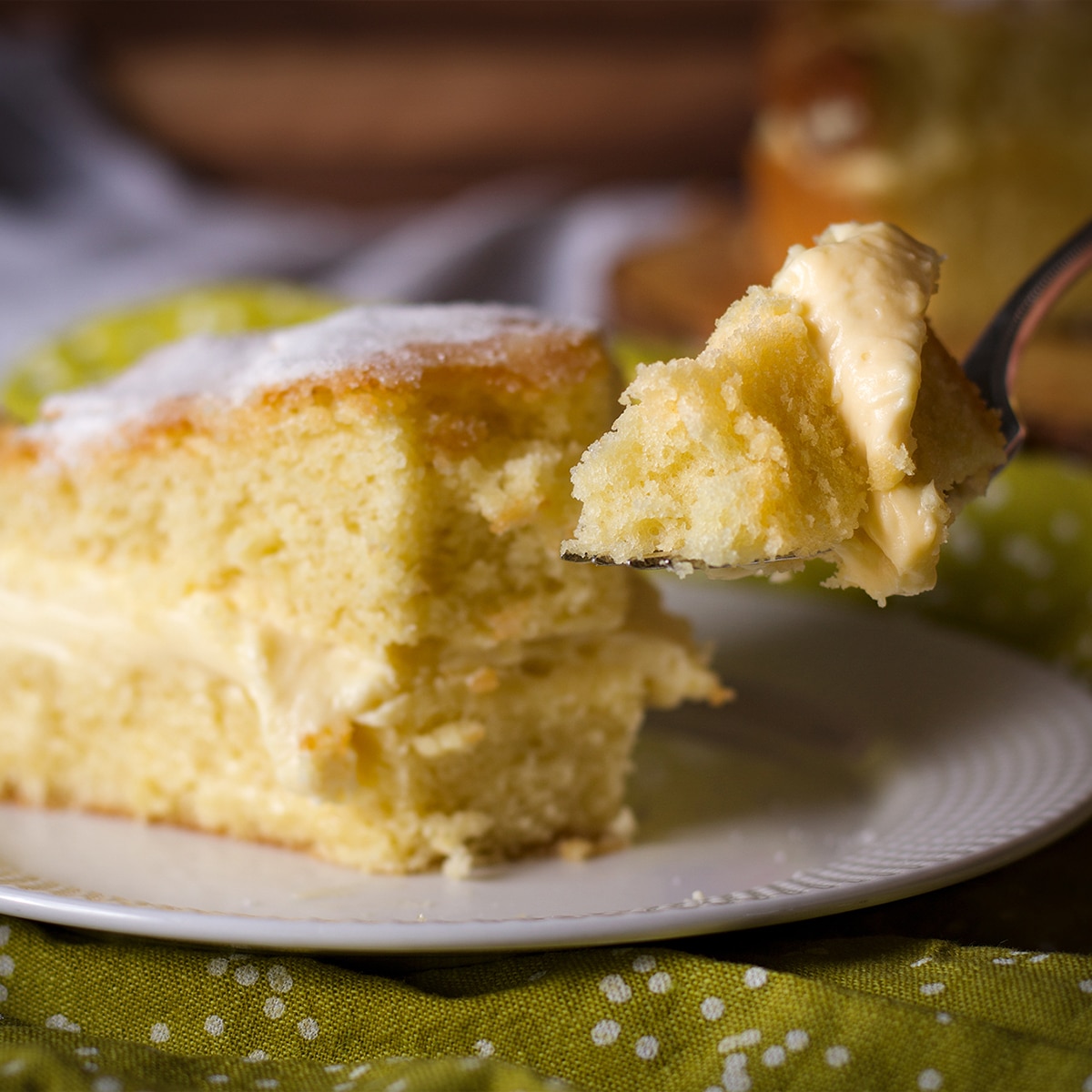 Someone cutting a bite of olive oil cake from a slice on a plate.