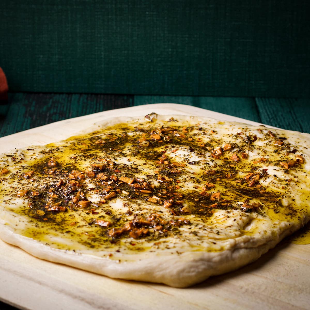 Pizza dough that's been covered in garlic herb oil.