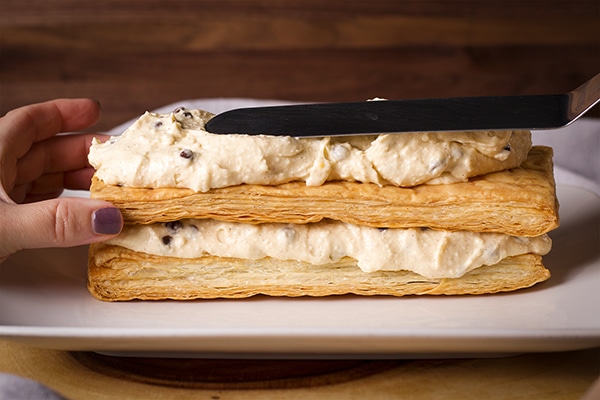 Spreading cannoli filling over layers of puff pastry for Cannoli Napoleon.