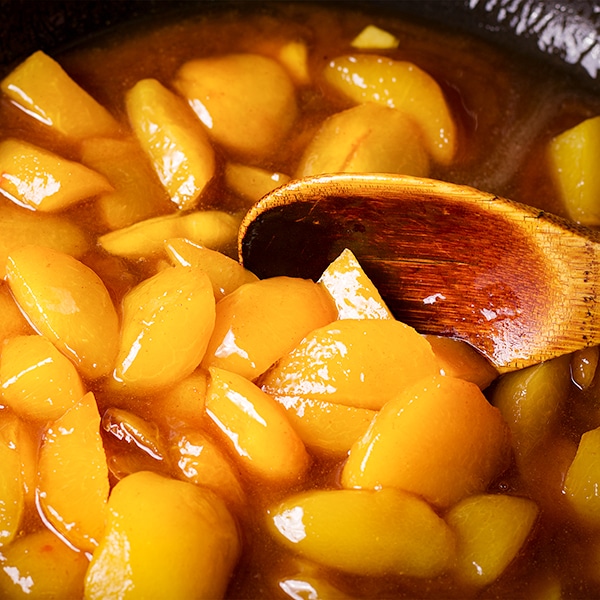 Stirring roasted fruit in brown butter maple sauce.