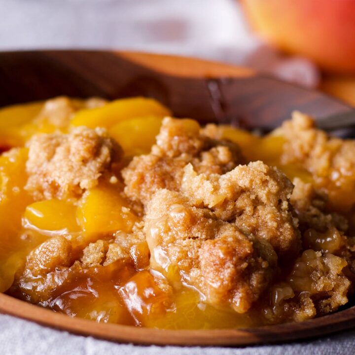 A wood bowl filled with warm peach cobbler.