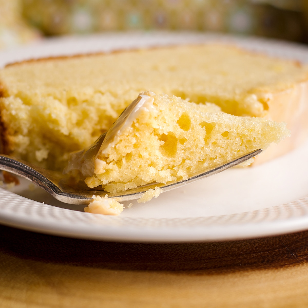 Using a fork to cut a bite from a slice of lemon loaf cake.