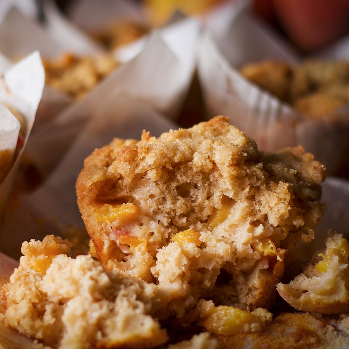 A peach cobbler muffin that's been broken in half so you can see the peach filled center of the muffin.