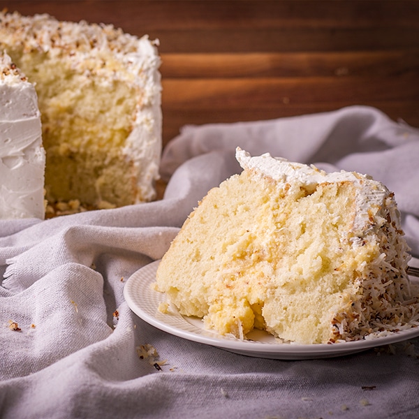 A slice of coconut cream cake on a plate, ready to eat.