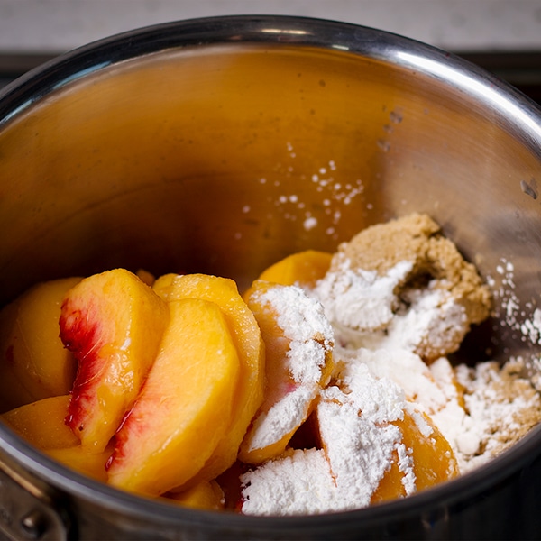 A saucepan filled with sliced peaches, brown sugar, salt, and cornstarch.