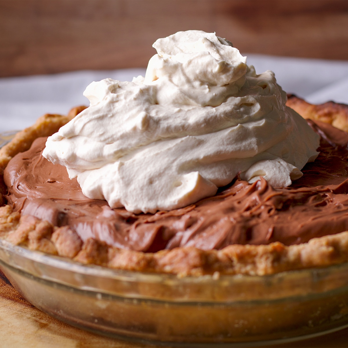 A chocolate cream pie that's just been topped with whipped cream.