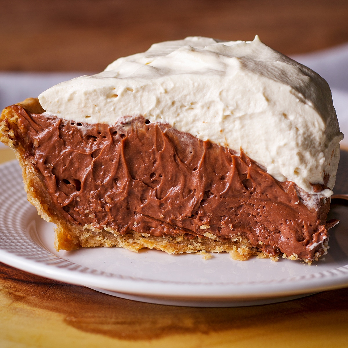A slice of chocolate cream pie topped with whipped cream on a white plate.