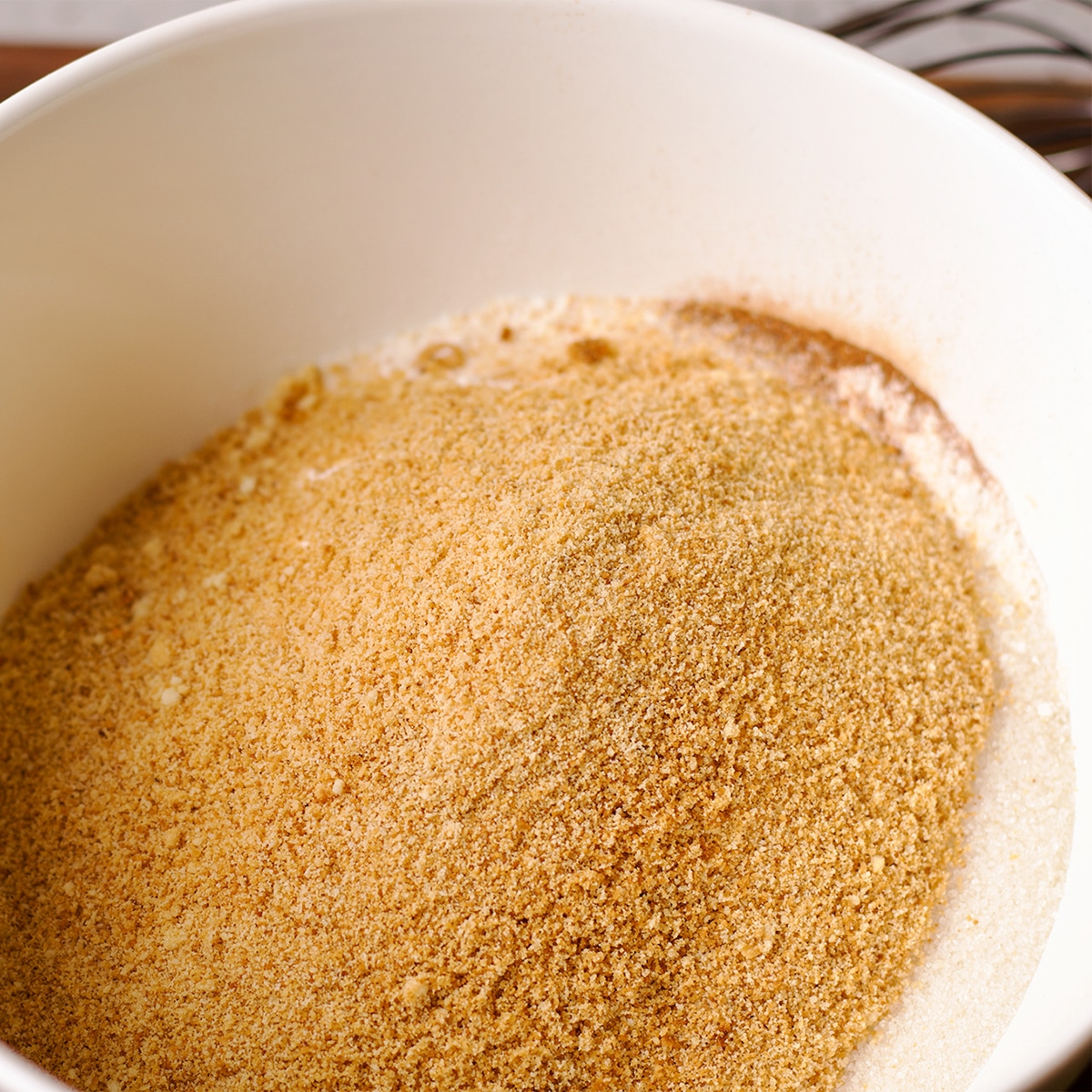 A white mixing bowl containing toasted almond flour, all-purpose flour, cinnamon, sugar, and salt.