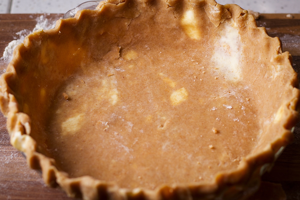 A pie plate lined with toasted almond pie crust dough.