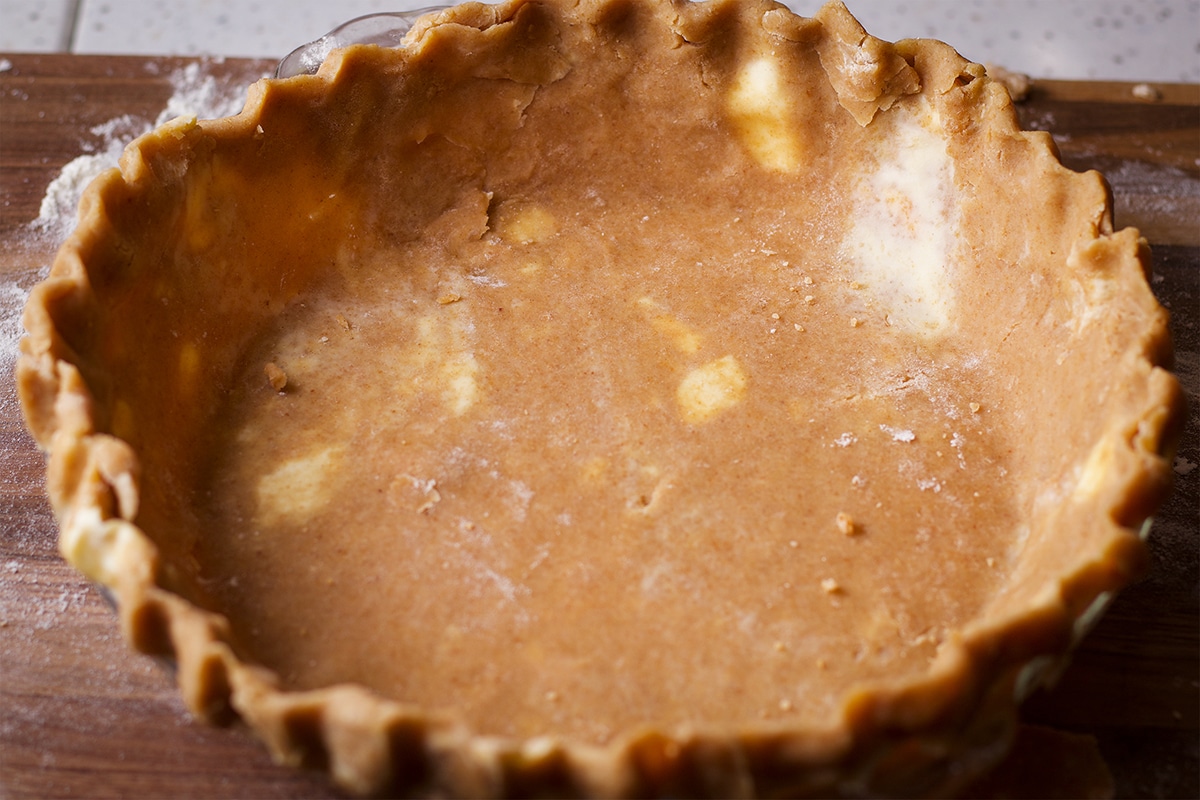 A pie plate lined with toasted almond pie crust dough.
