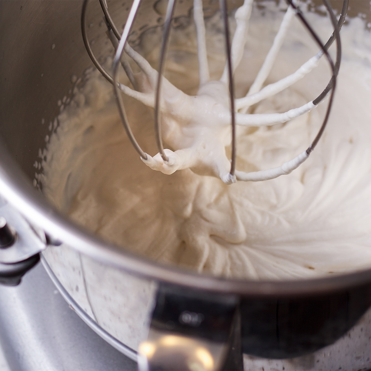 Looking down into the bowl of a stand mixer filled with whipped cream.