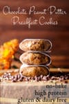 Three parchment wrapped no-bake, high protein breakfast cookies stacked on top of each other on a wooden tray.