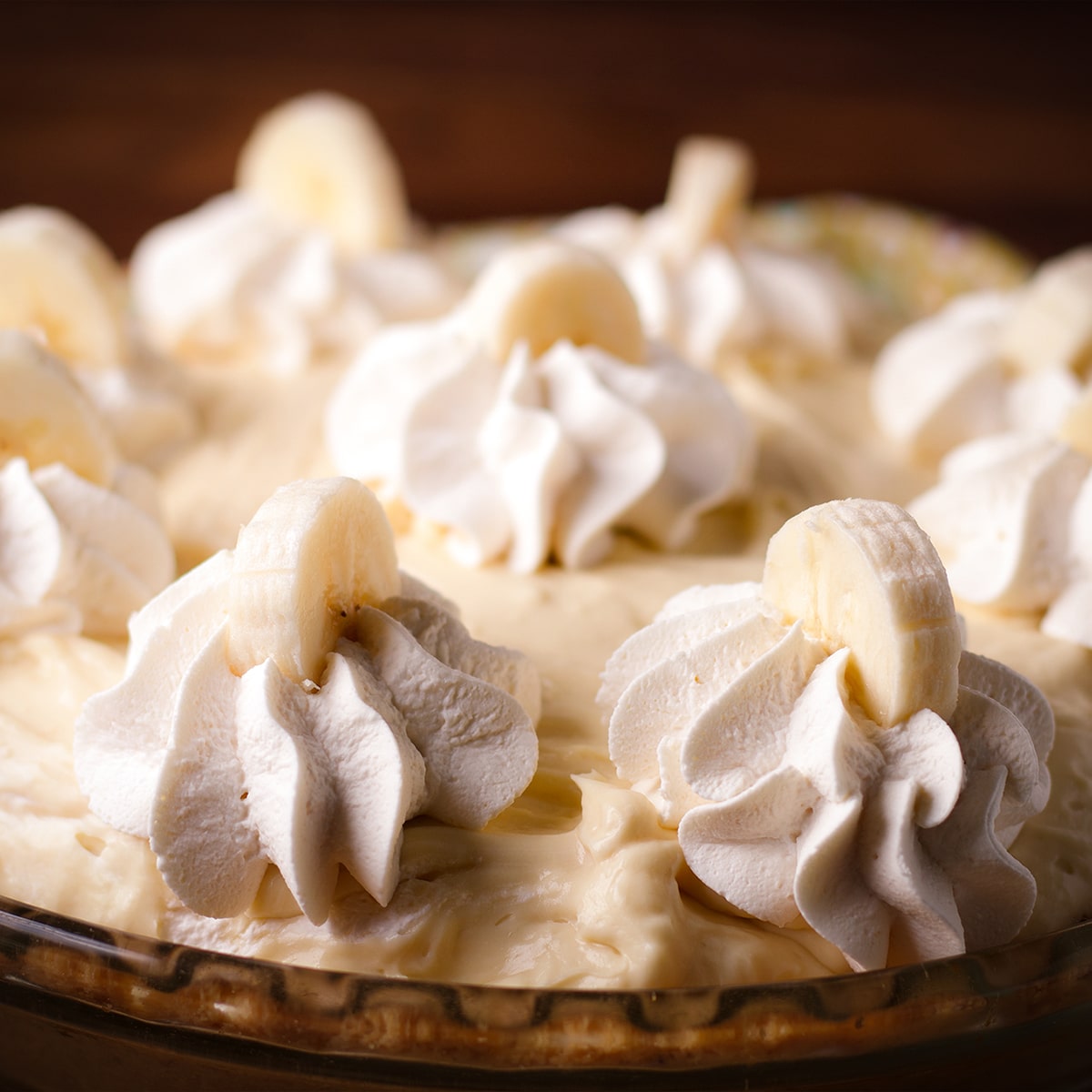 A black bottom banana cream pie that's been decorated with whipped cream and slices of banana.