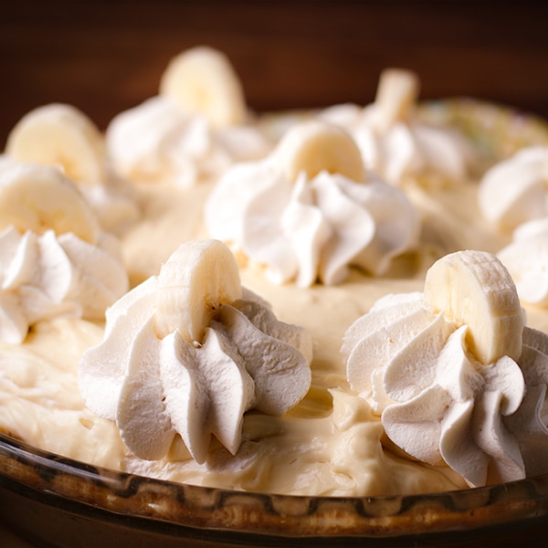 A Black Bottom Banana Cream Pie decorated with whipped cream and slices of banana.