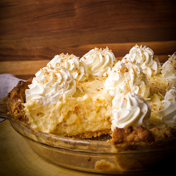 A coconut cream pie with a slice taken out of it.