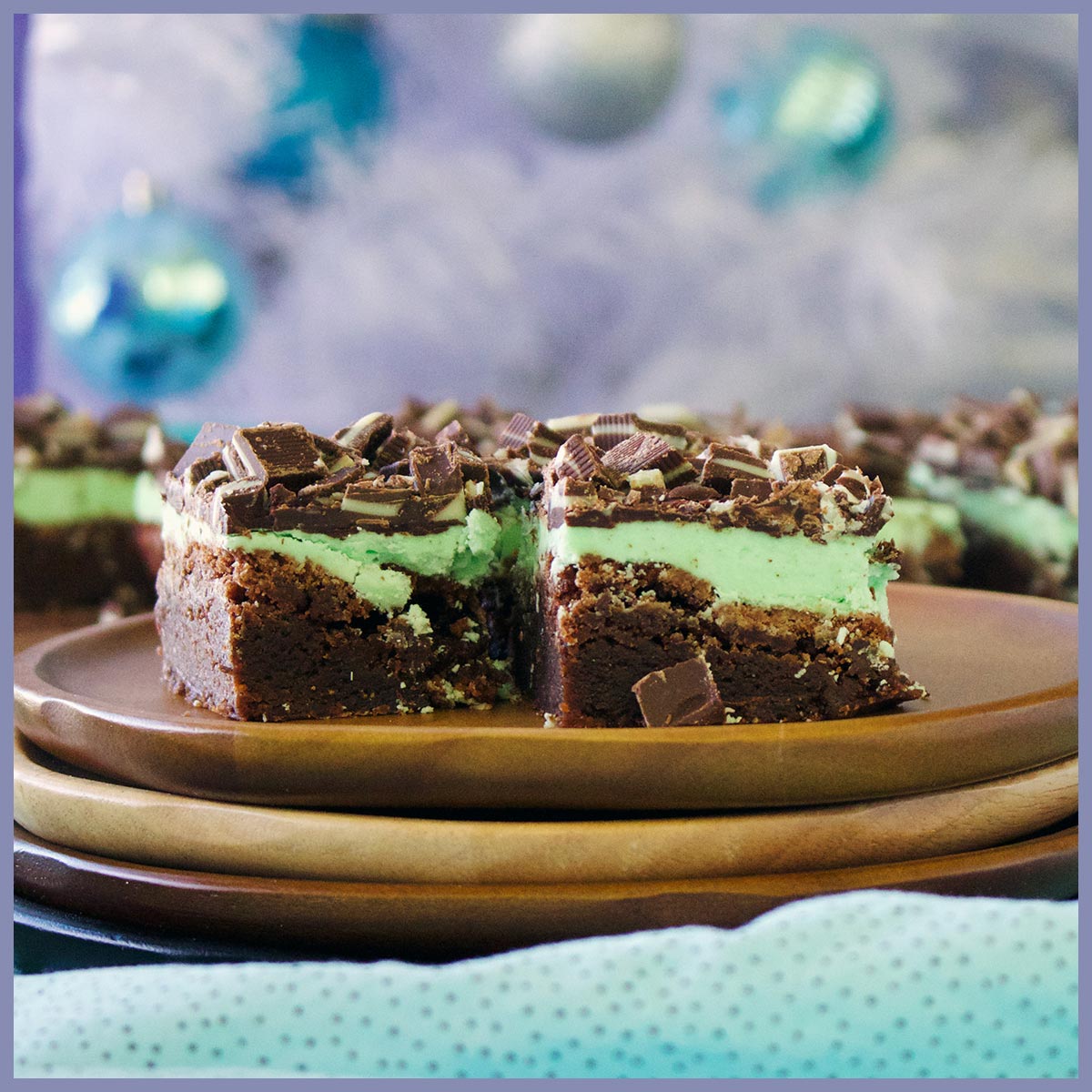 Two mint chocolate brownies on a wood plate.
