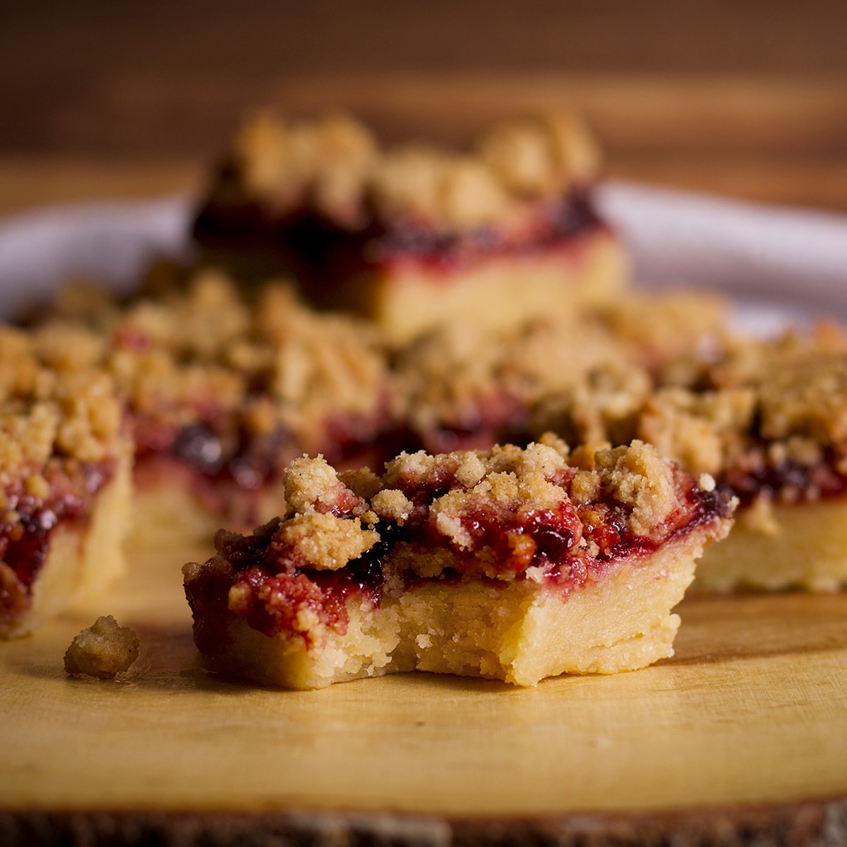 A closeup photo of a cherry crumble bar with a bite taken out of it.