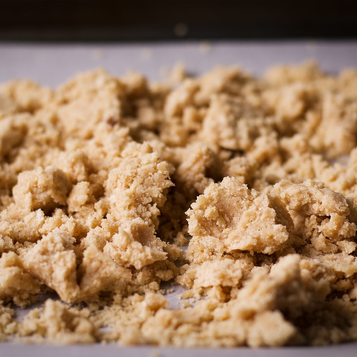 Crumb topping for cherry crumble bars spread out on a piece of parchment paper.