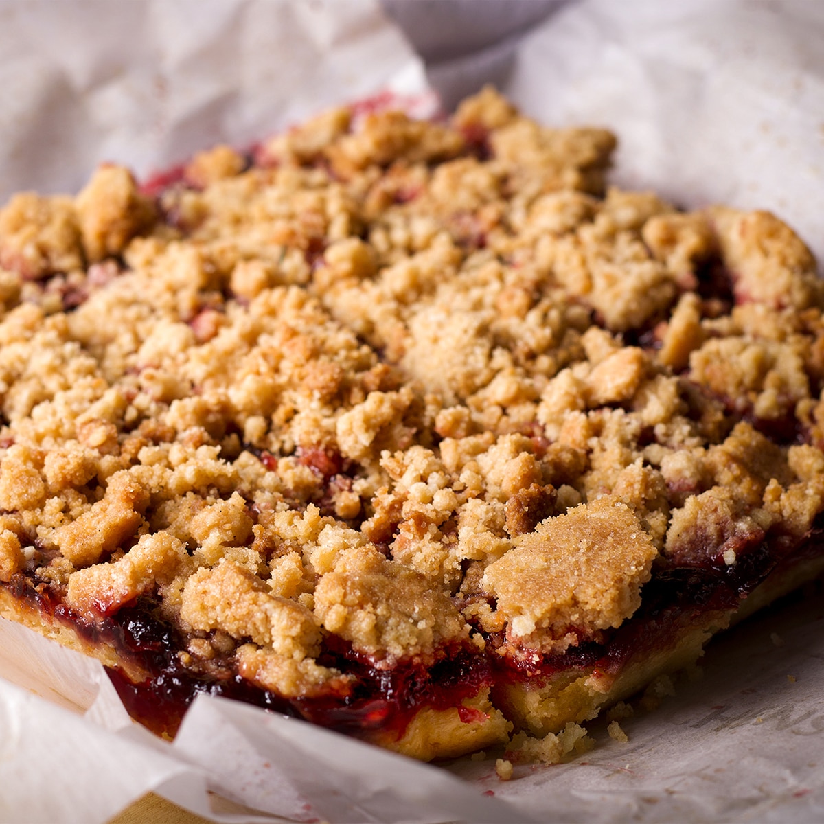Freshly baked cherry bars with a crumble topping that have just been removed from their baking dish.