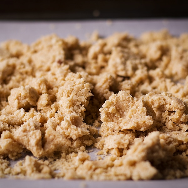 A baking sheet with the crumb topping spread over it for cherry shortbread crumble bars.
