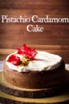 A Pistachio Cardamom Cake frosted with Cream Cheese Buttercream on a wooden tray.