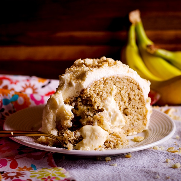 A slice of Banana Cream Cake on a plate with a fork.