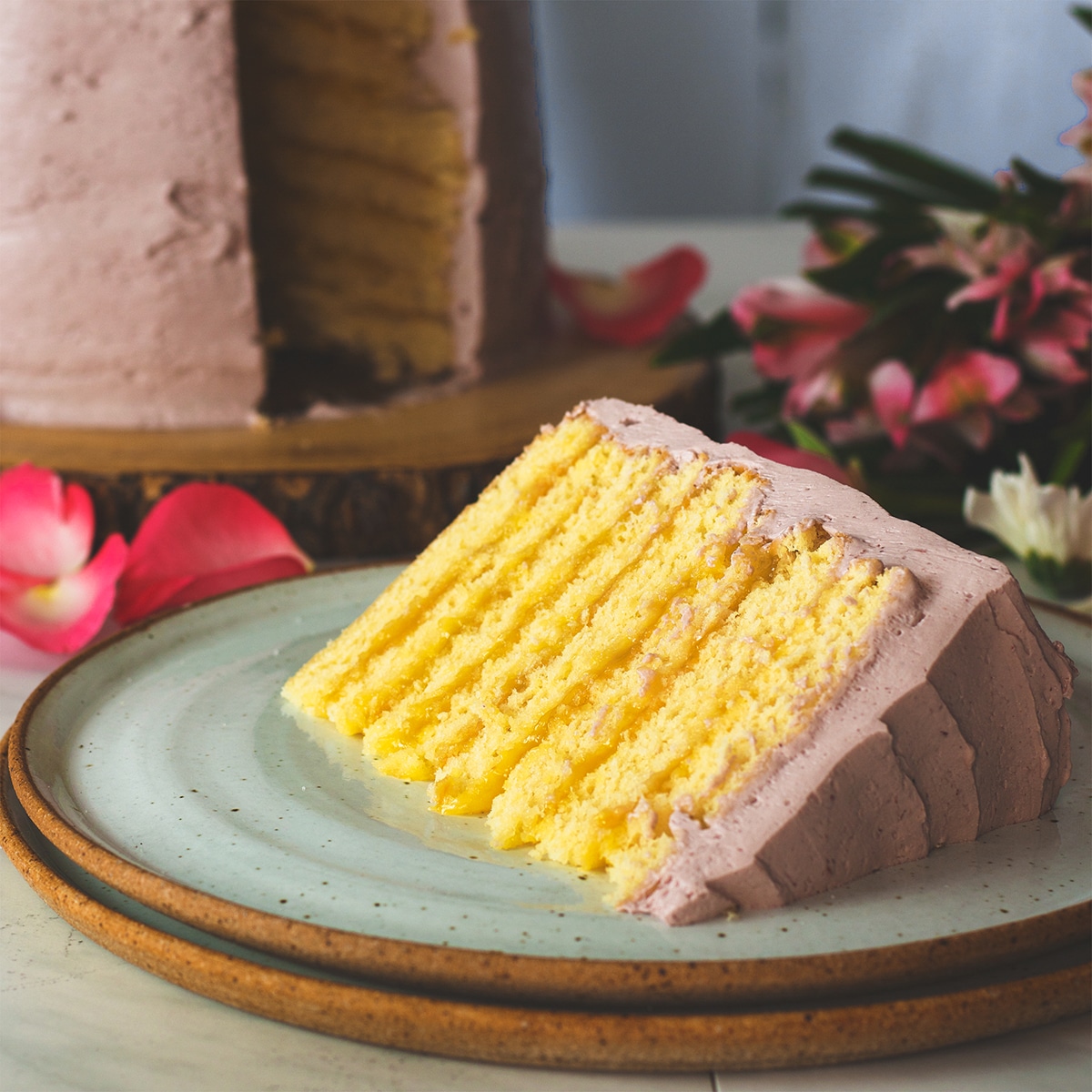 A slice of lemon layer cake on a plate, ready to eat.