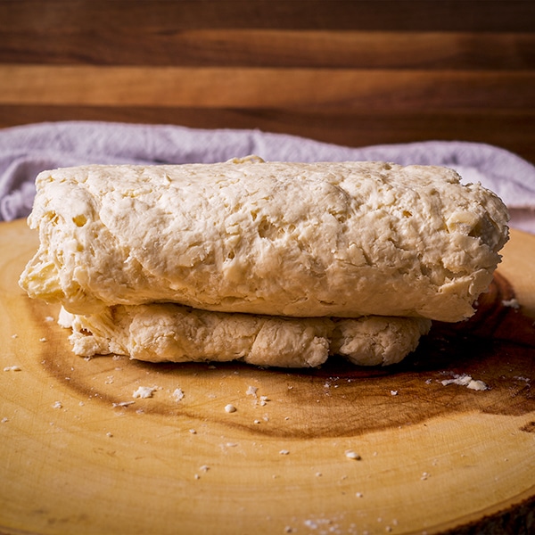 Folding over the dough of buttermilk biscuits to create layers.