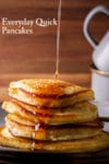 Pouring syrup over a stack of pancakes on a plate.
