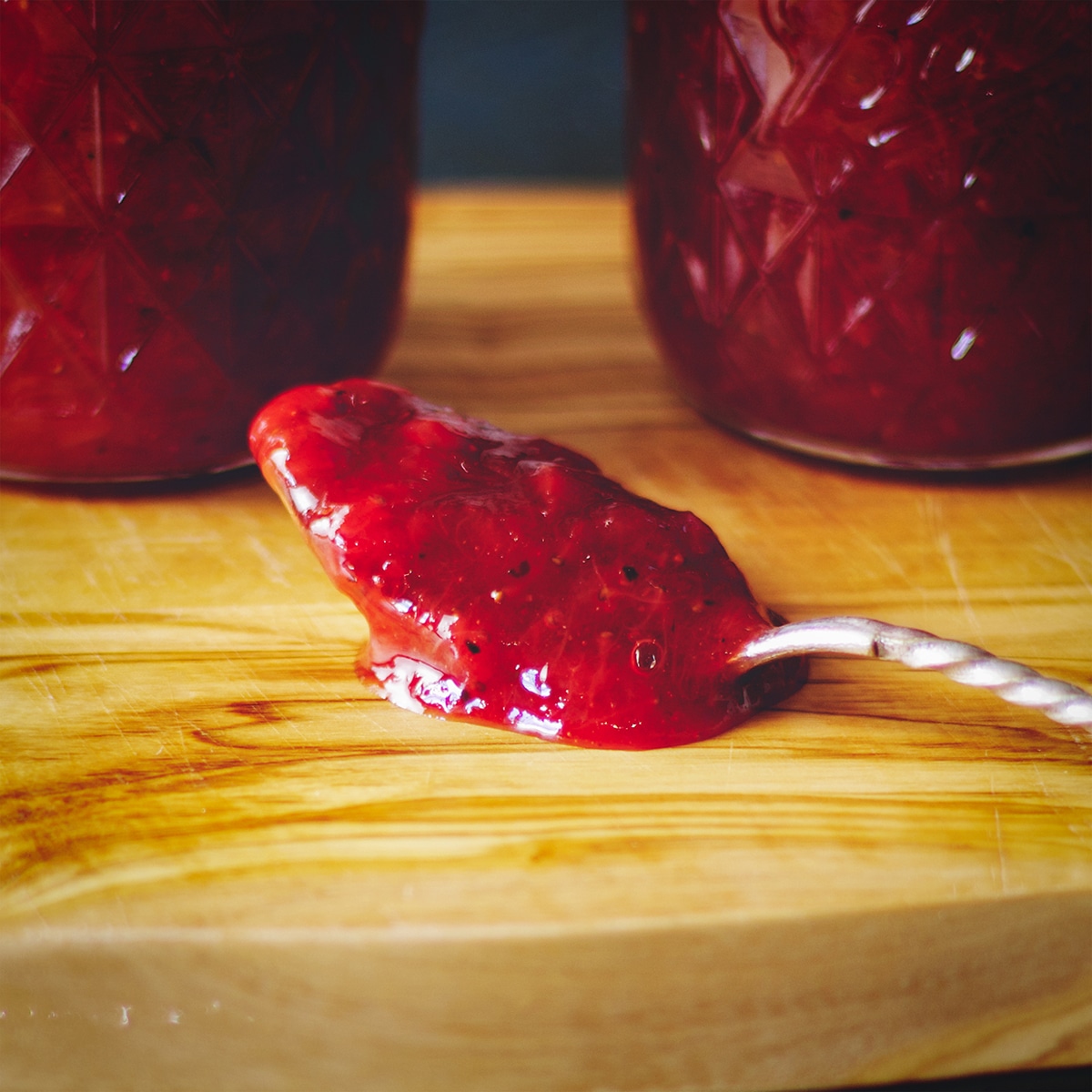 A spoonful of homemade strawberry rhubarb jam that's thick enough to cling to the spoon.