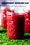 Several jars of homemade strawberry rhubarb jam lined up on a bright green surface.