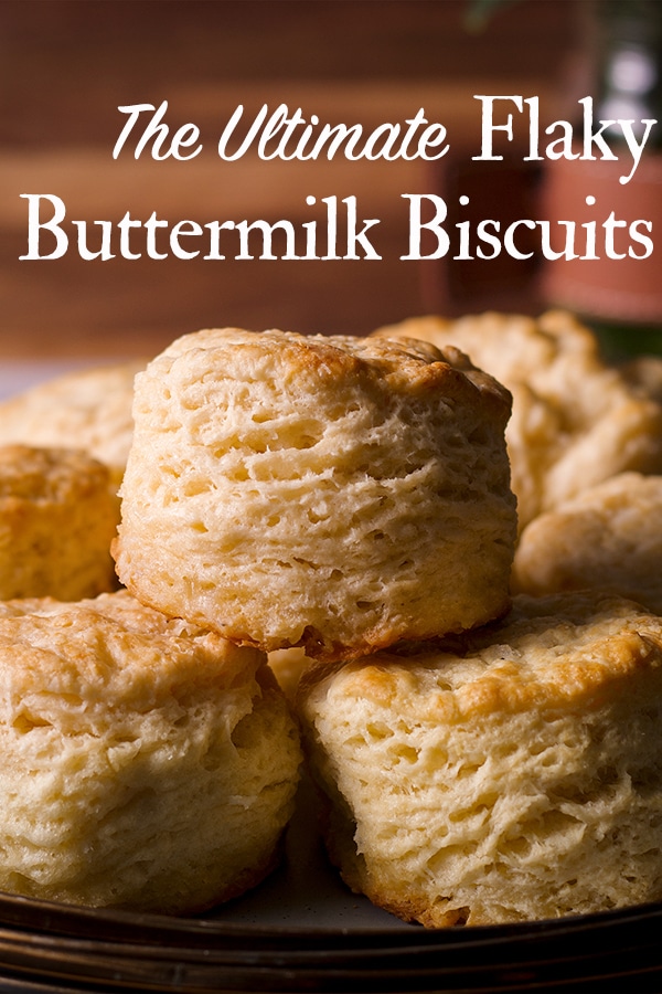 A wood tray with several freshly baked buttermilk biscuits on it.