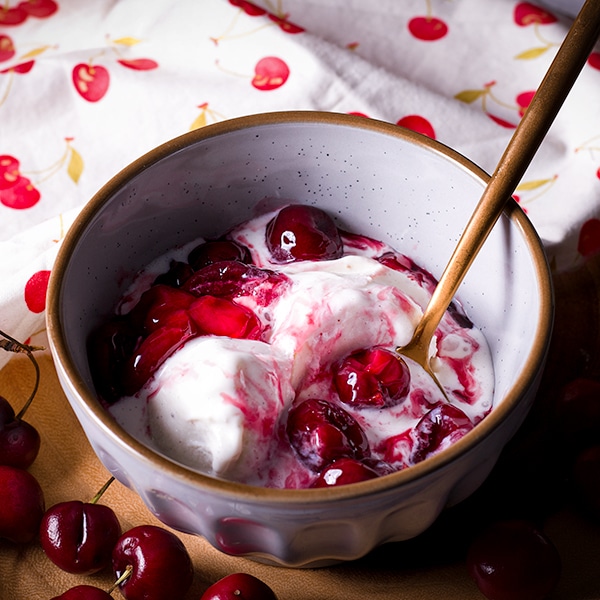 A bowl of vanilla ice cream topped with homemade cherry sauce.