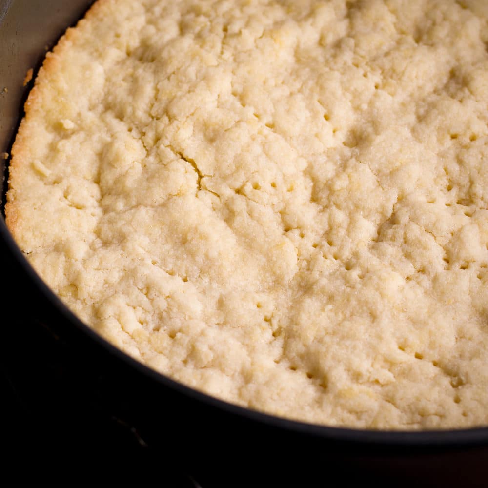 The golden, partially pre-baked crust of a New York Style Cheesecake.