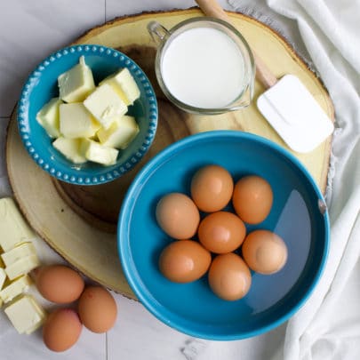 Butter, eggs, and milk set out on a wood tray.