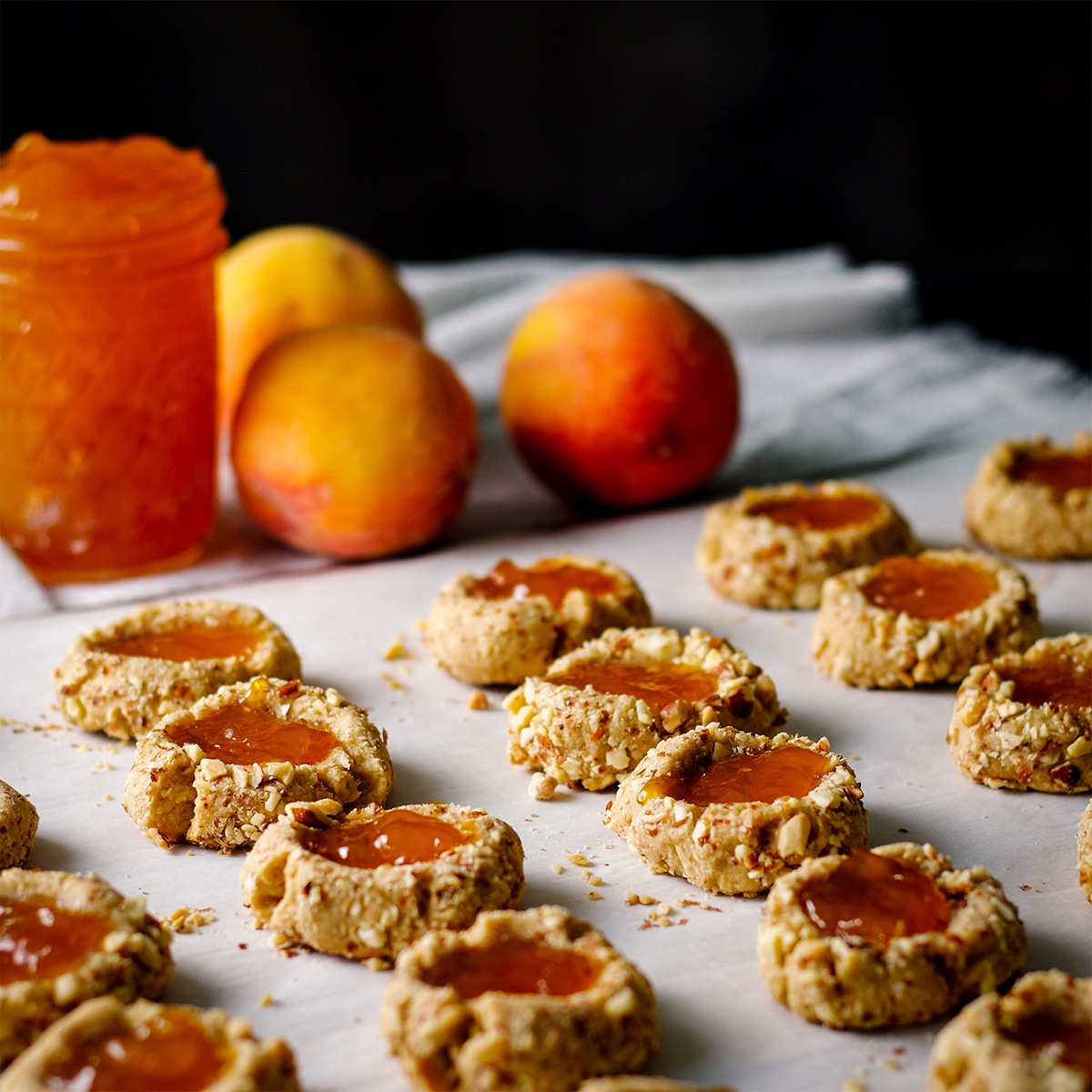 A tray of almond thumbprint cookies filled with peach preserves ready to bake.