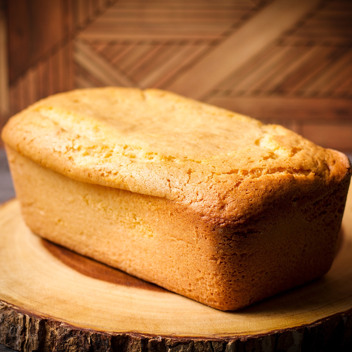A vanilla loaf cake resting on a wood cutting board.