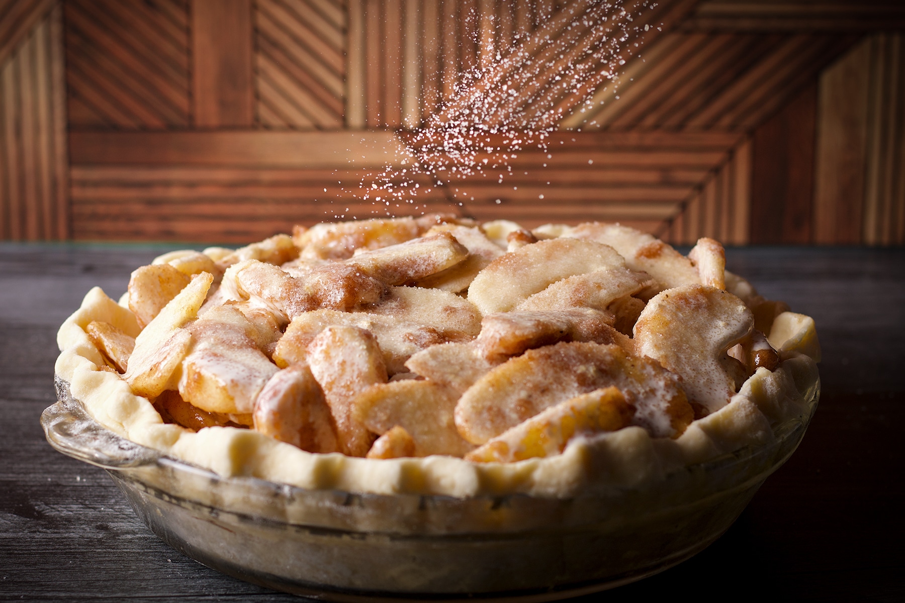 Sprinkling sugar over the top of a German Apple Pie before baking it.