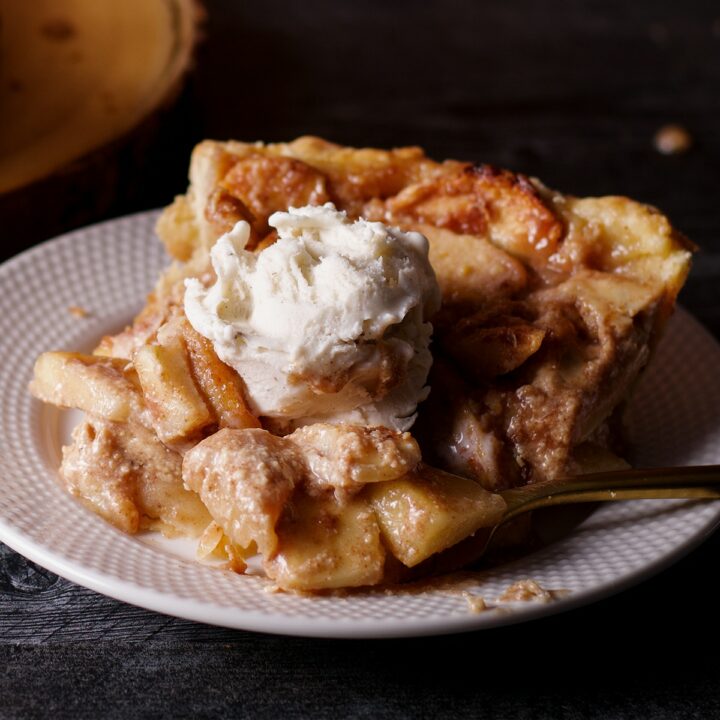 A slice of German Apple Pie topped with a scoop of vanilla ice cream.